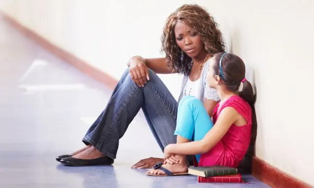 School counselor sitting with a student in a hallway, providing one-on-one behavioral support